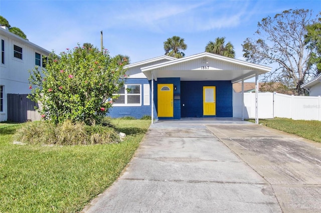 view of front facade featuring concrete driveway, a front lawn, fence, and an attached carport