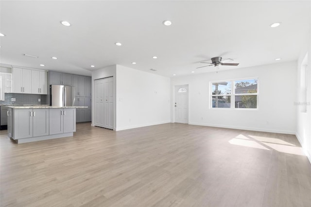 unfurnished living room featuring a ceiling fan, recessed lighting, light wood-style flooring, and baseboards