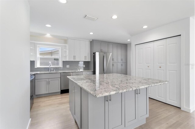 kitchen with appliances with stainless steel finishes, visible vents, a sink, and gray cabinetry