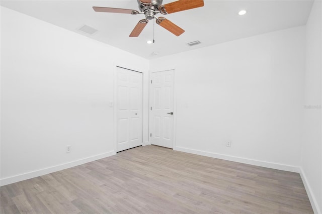 spare room featuring light wood finished floors, visible vents, and baseboards