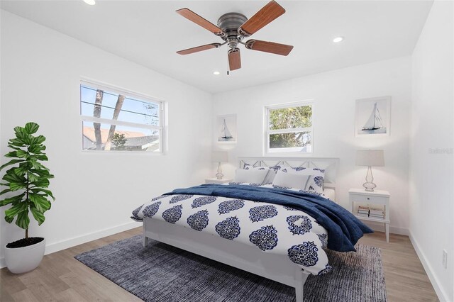 bedroom featuring light wood-type flooring, multiple windows, and baseboards