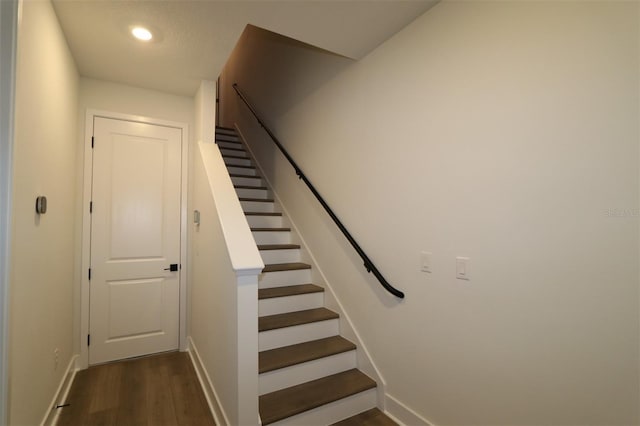 staircase featuring baseboards, wood finished floors, and recessed lighting