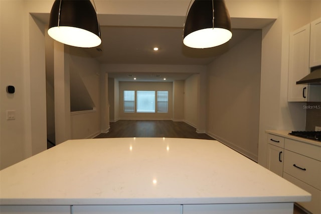 kitchen featuring white cabinets, light countertops, a kitchen island, and dark wood-style flooring