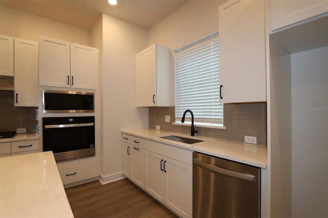 kitchen with decorative backsplash, stainless steel appliances, light countertops, white cabinetry, and a sink