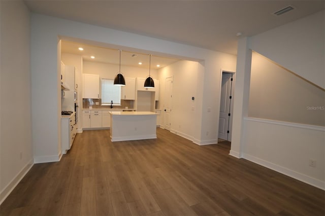 kitchen featuring white cabinets, dark wood-type flooring, visible vents, and a center island