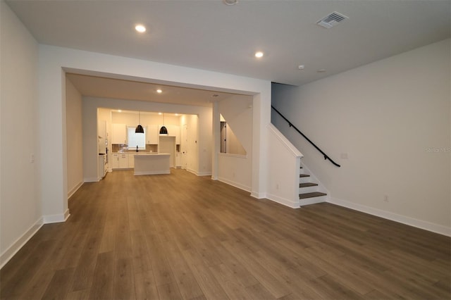 unfurnished living room featuring dark wood-style flooring, recessed lighting, visible vents, stairway, and baseboards