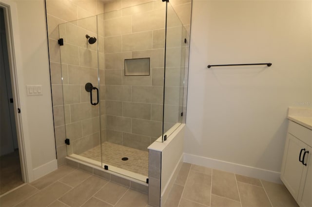 bathroom with tile patterned flooring, baseboards, a shower stall, and vanity