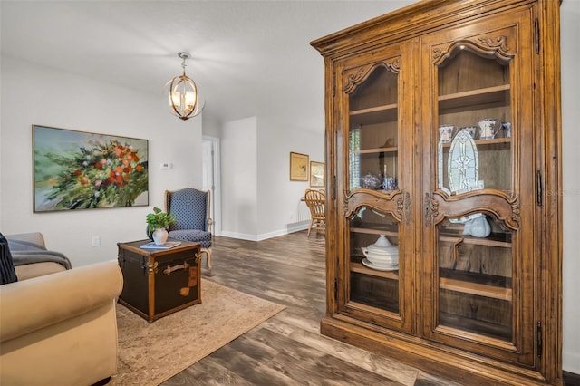 living area featuring baseboards, dark wood finished floors, and a notable chandelier