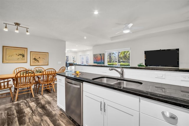 kitchen featuring dark wood-style floors, stainless steel dishwasher, white cabinetry, a sink, and dark stone countertops