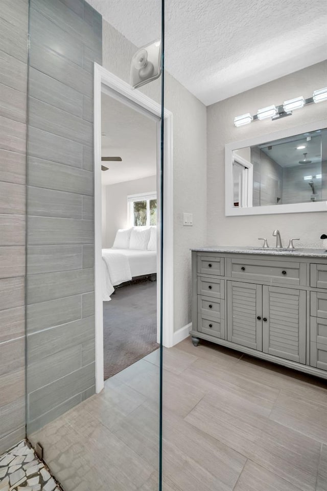 bathroom featuring ensuite bathroom, a textured ceiling, vanity, baseboards, and tile patterned floors