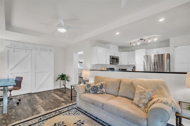 living area with baseboards, a raised ceiling, dark wood finished floors, ceiling fan, and recessed lighting