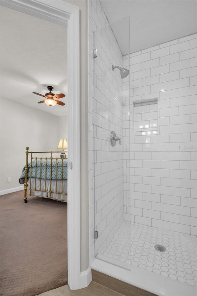 ensuite bathroom with a shower stall, baseboards, ceiling fan, and ensuite bathroom