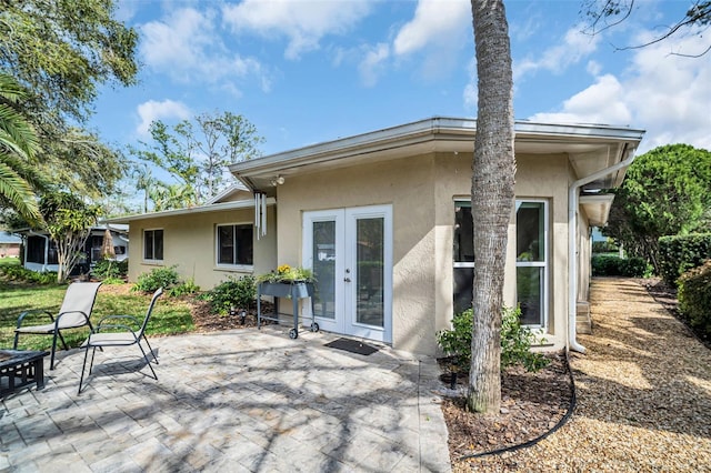 rear view of property with french doors, a patio area, and stucco siding