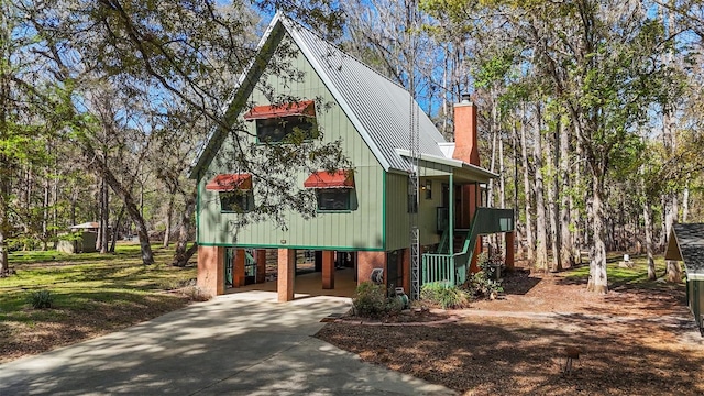 view of front of home featuring a chimney, metal roof, a carport, and concrete driveway