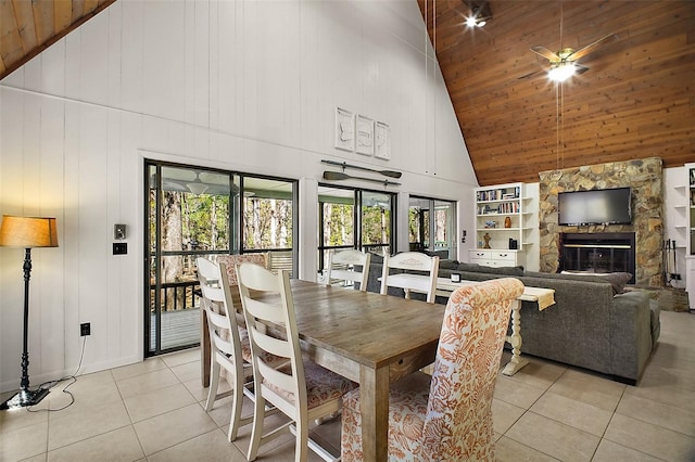 dining area featuring light tile patterned floors, a stone fireplace, wooden ceiling, and built in features