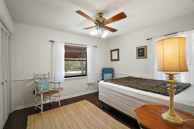 bedroom with a closet, a ceiling fan, a textured ceiling, wood finished floors, and baseboards