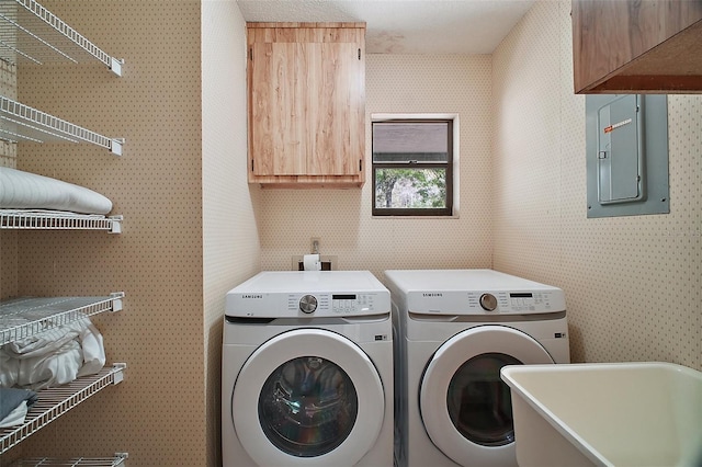 washroom with a sink, washer and dryer, electric panel, cabinet space, and wallpapered walls