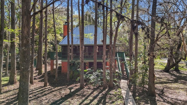 back of property featuring a sunroom, stairs, and a chimney