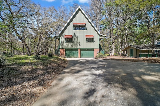 view of side of property with driveway, an attached garage, and brick siding