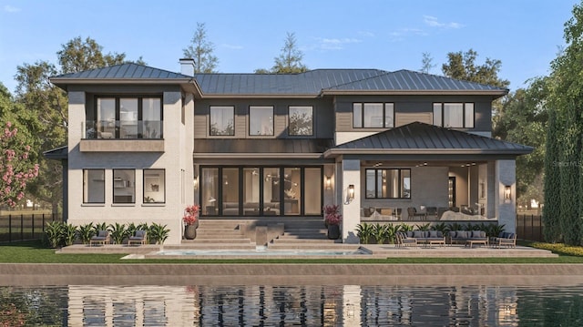 back of property with metal roof, a standing seam roof, a patio, and an outdoor living space