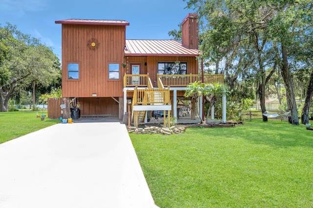 view of front of property featuring a front lawn, concrete driveway, metal roof, a carport, and a standing seam roof