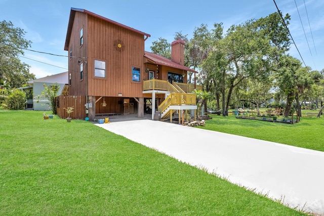 back of property with a carport, stairs, a chimney, and a lawn