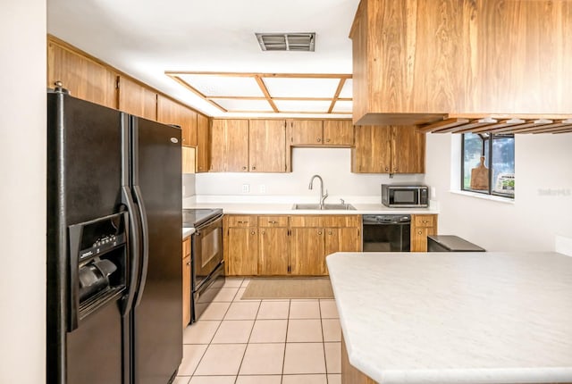 kitchen with visible vents, black appliances, a sink, light countertops, and light tile patterned floors