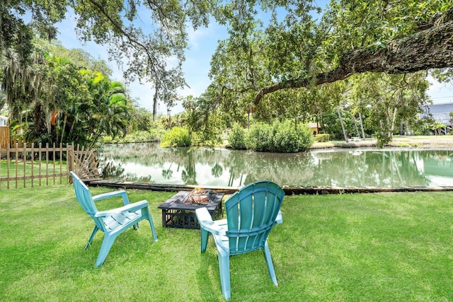 view of yard with fence, a water view, and an outdoor fire pit
