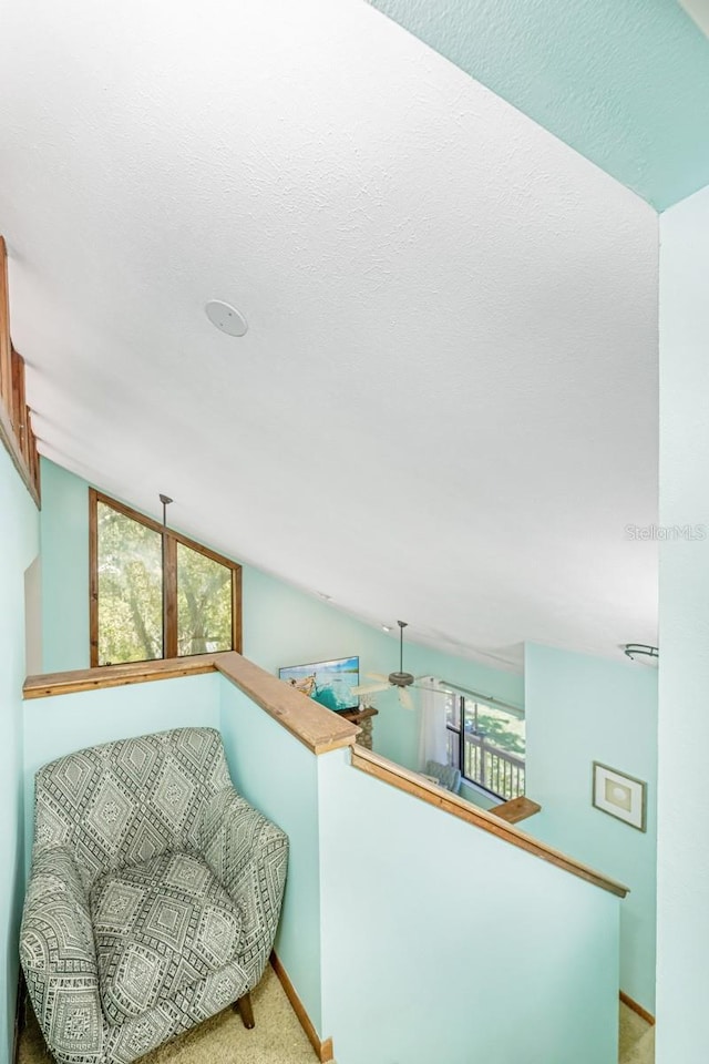 living area featuring baseboards, carpet floors, an upstairs landing, and vaulted ceiling