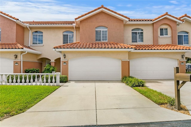 mediterranean / spanish house with a garage, driveway, a tiled roof, and stucco siding