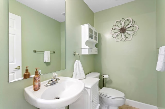 bathroom featuring tile patterned flooring, baseboards, a sink, and toilet