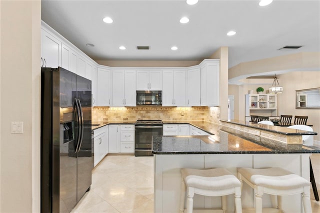 kitchen with range with electric cooktop, visible vents, stainless steel microwave, a breakfast bar, and refrigerator with ice dispenser