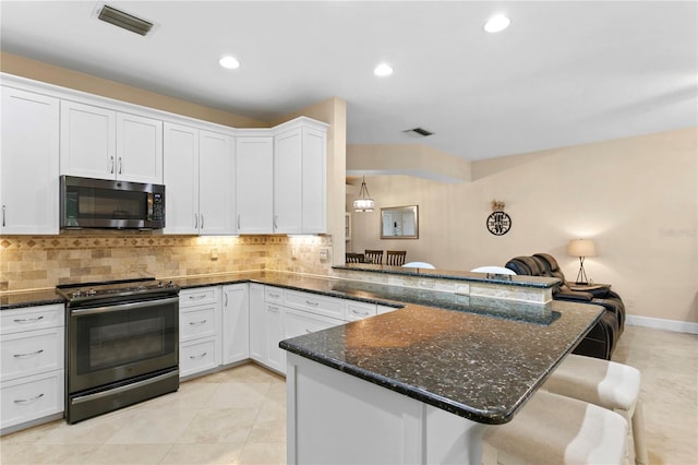 kitchen with decorative backsplash, stainless steel microwave, visible vents, and black / electric stove