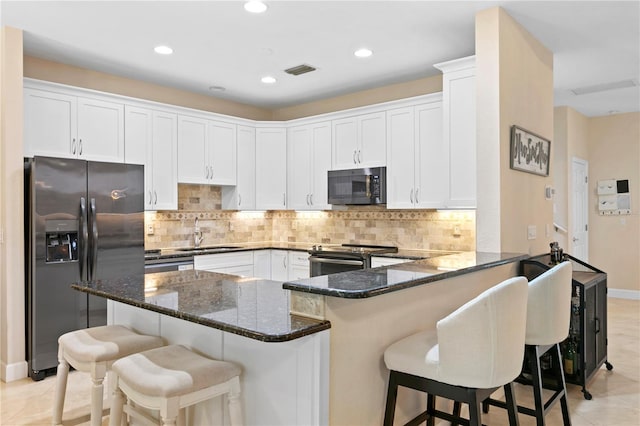 kitchen featuring range with electric cooktop, stainless steel fridge with ice dispenser, dark stone countertops, a peninsula, and a sink