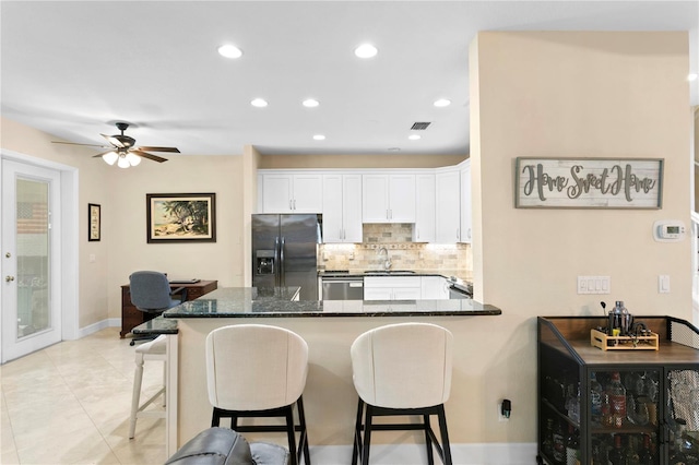 kitchen with white cabinets, a peninsula, a sink, refrigerator with ice dispenser, and stainless steel dishwasher