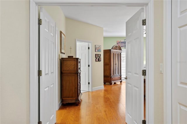 corridor with light wood-style flooring and baseboards