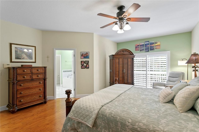 bedroom with ensuite bath, ceiling fan, baseboards, and wood finished floors