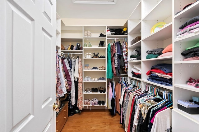 walk in closet featuring attic access and wood finished floors