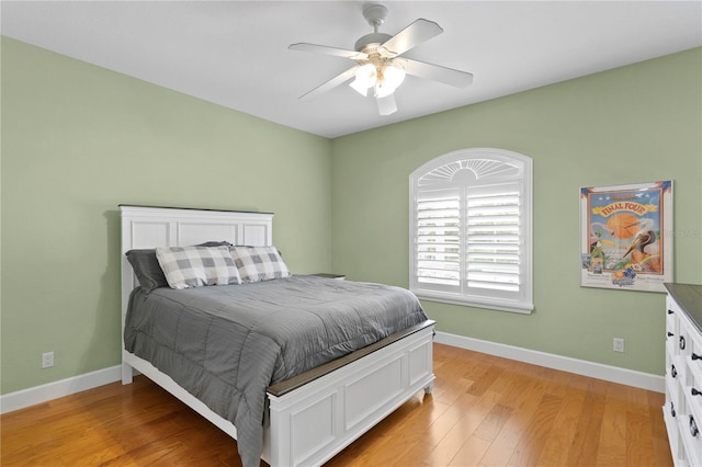 bedroom with baseboards, a ceiling fan, and light wood-style floors