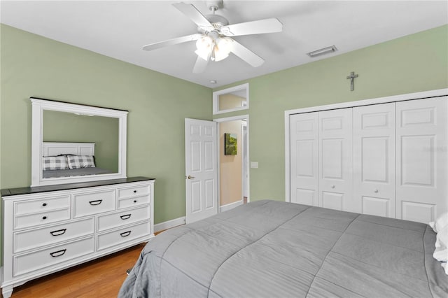 bedroom with ceiling fan, a closet, wood finished floors, and visible vents