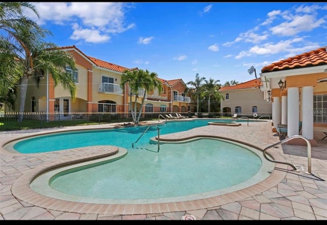 community pool with a patio area and fence