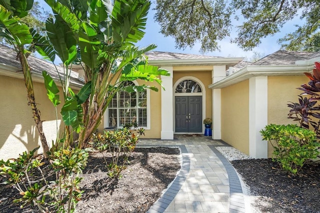 property entrance featuring roof with shingles and stucco siding