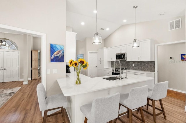 kitchen featuring a breakfast bar, stainless steel microwave, a sink, and visible vents