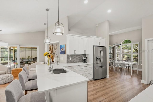 kitchen with a sink, a peninsula, light wood finished floors, and stainless steel fridge