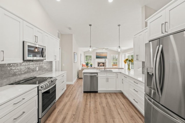 kitchen featuring a sink, white cabinetry, open floor plan, appliances with stainless steel finishes, and backsplash