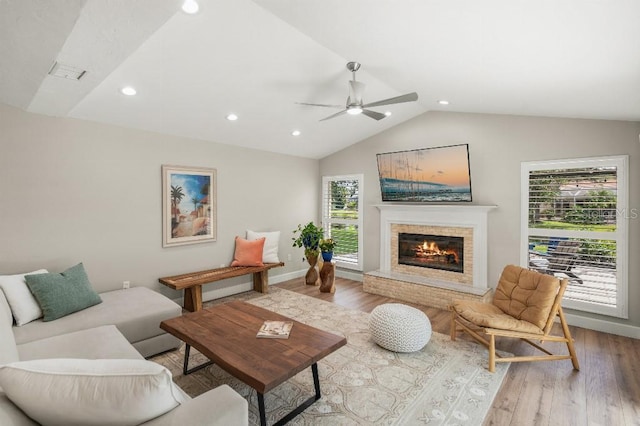 living room featuring lofted ceiling, a fireplace, plenty of natural light, and wood finished floors