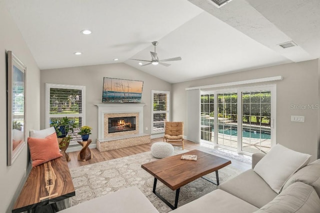 living room featuring lofted ceiling, recessed lighting, a fireplace, wood finished floors, and baseboards