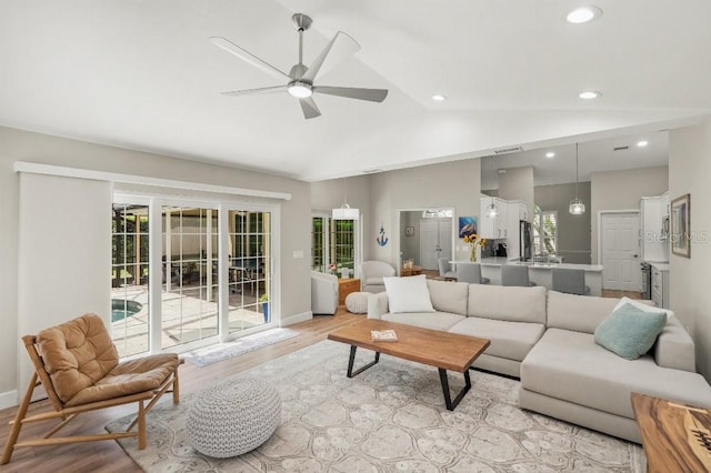 living room with baseboards, lofted ceiling, ceiling fan, light wood-type flooring, and recessed lighting