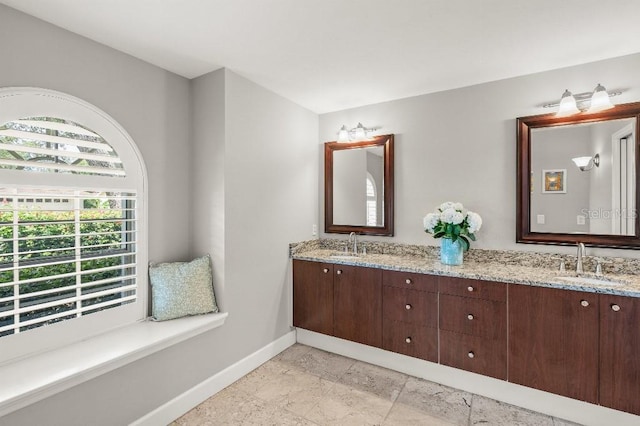 bathroom with a sink, baseboards, and double vanity