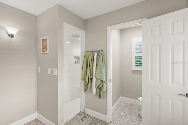 bathroom with toilet, baseboards, and a walk in shower